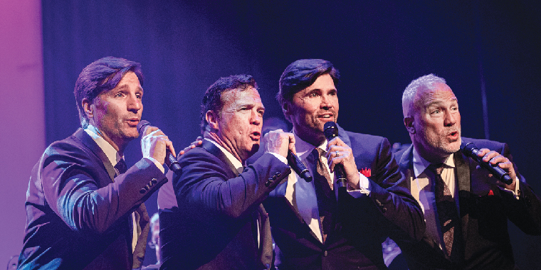 The Four Phantom singers on stage performing. 