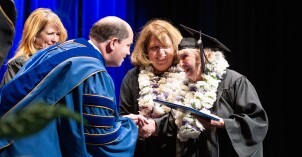 An elderly graduate receives her diploma during a convocation at BYU-Idaho in July 2024.