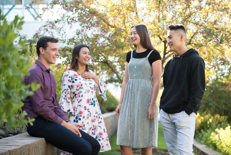 Four Students talk and laugh outside.