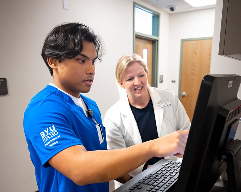 Nursing student looking at a computer with his instructor