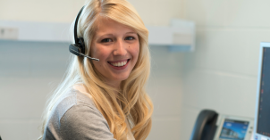 A female student smiles while taking a call at an on-campus call center.