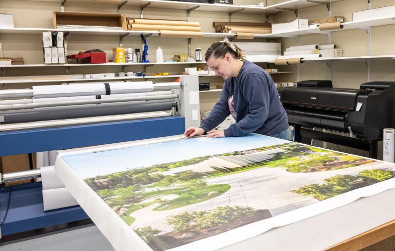 An employee works on a banner with the Taylor building printed on it