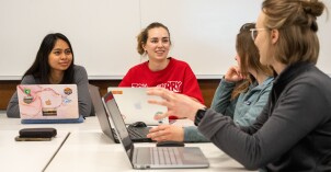 Students sitting together at a table working on their computers