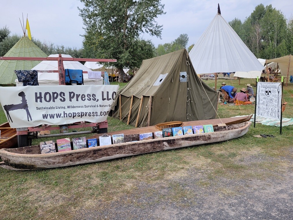 A tent with a canoe in front holding books.