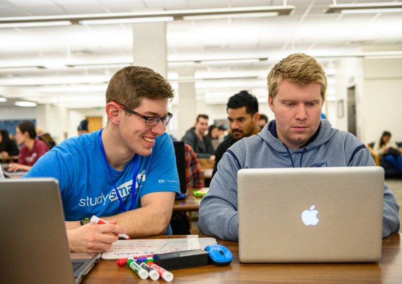A BYU-Idaho student tutor smiles while helping another student with an assignment.
