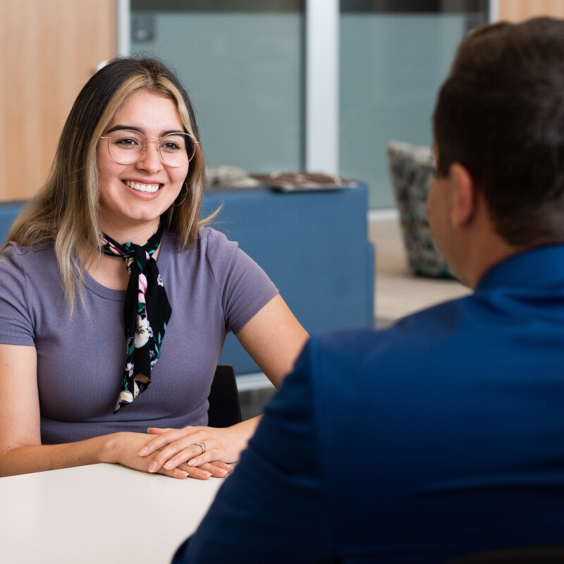 A female student wearing glasses smiles during an interview.