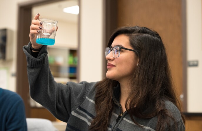 A female BYU-Idaho Biomedical Science student observes a chemical reaction during an experiment