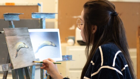 An artist paints a still life in class of a browning banana.