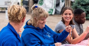A BYU-Idaho student smiles as she helps a special needs woman with a craft.