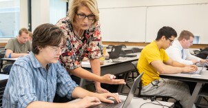 A professor helps a student with class work on her laptop