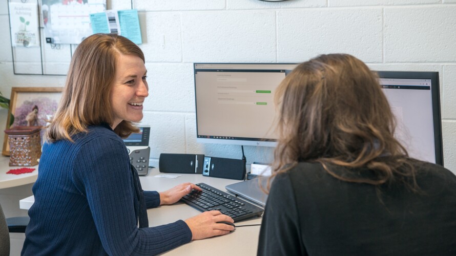 A BYU-Idaho Career and Academic Advising employee smiles while counseling a student.