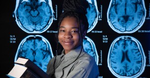 A Neuroscience student holds two books in front of brain x-rays.