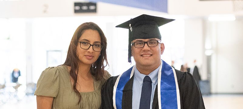 Graduate standing with his wife