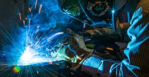 A student wearing welding gear, sees sparks fly as he welds a sheet of metal during a engineering technology lab course.