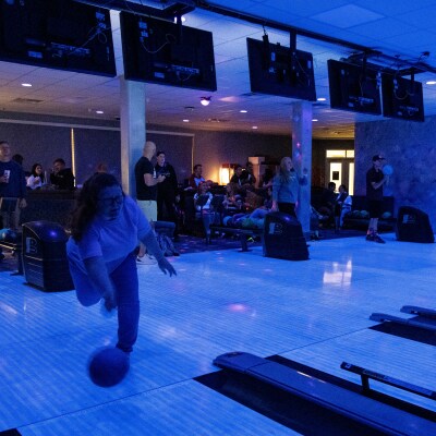 A nursing student throwing a bowling ball down the alley