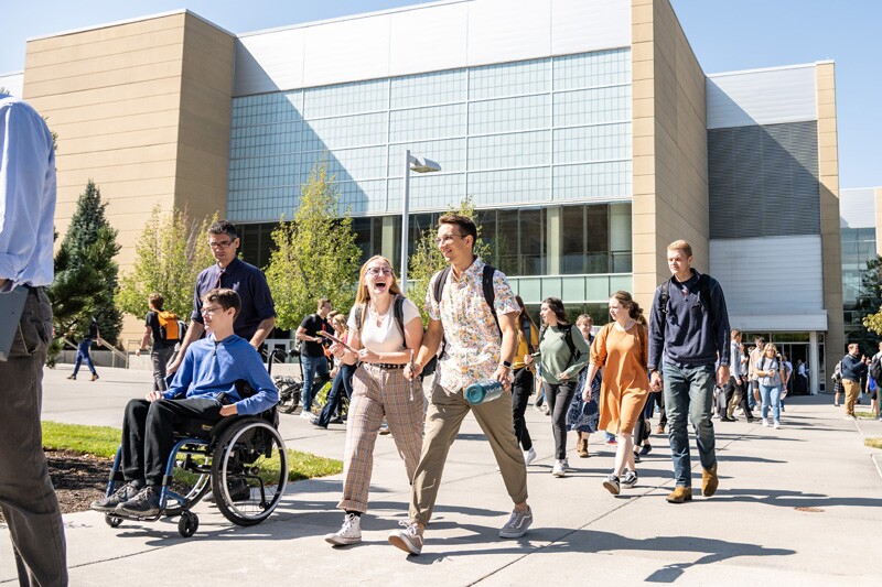 A crowd of students walk through campus