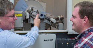 A professor shows and explains a piece of machinery to a student.