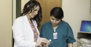 A physician and a student majoring in Allied Health looks over a container of medicine in a medical clinic.