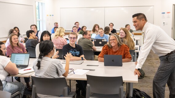 An early education student talks with her professor and classmates.