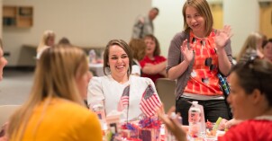 Women sitting around a table talking and laughing at the Women's Luncheon