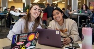Students sitting at a table and working on their computers.