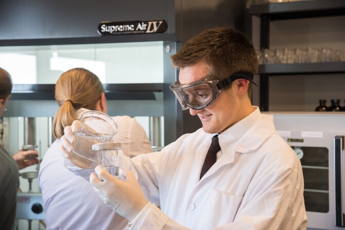 A male student working on a project in the Food Science Research Lab with two other students in the background.