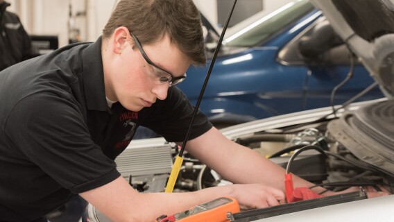 A student works on a car in an Advanced Vehicle Systems Lab.