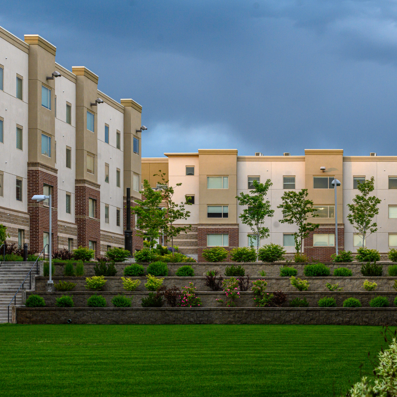 A courtyard view of the Centre Square Apartments, with terraced trees, shrubbery, and lawn. Centre Square Apartments is a common setting for daily student life at BYU-Idaho.