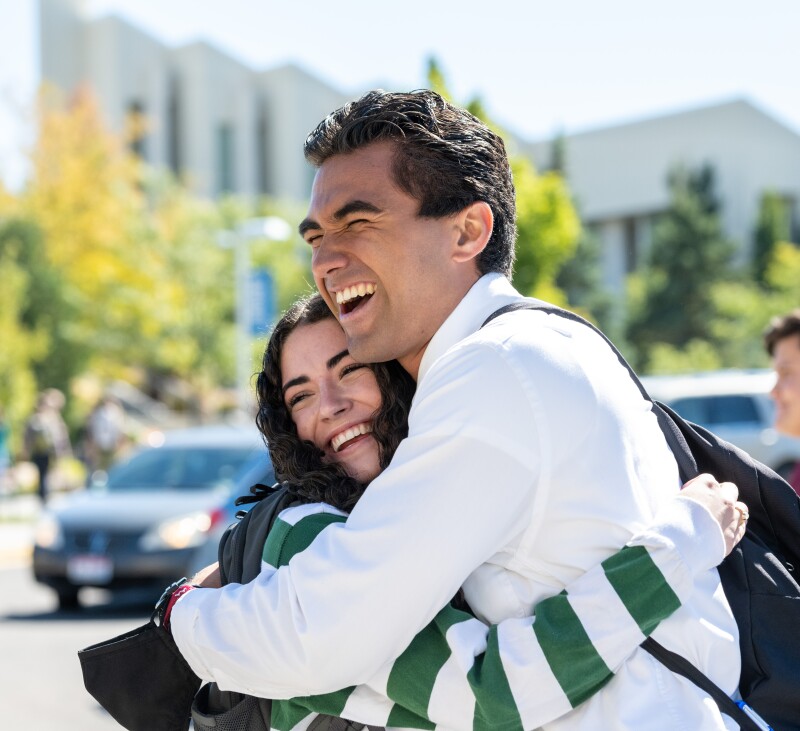 A male student and female student smile and embrace after a devotional meeting on the BYU-Idaho campus.