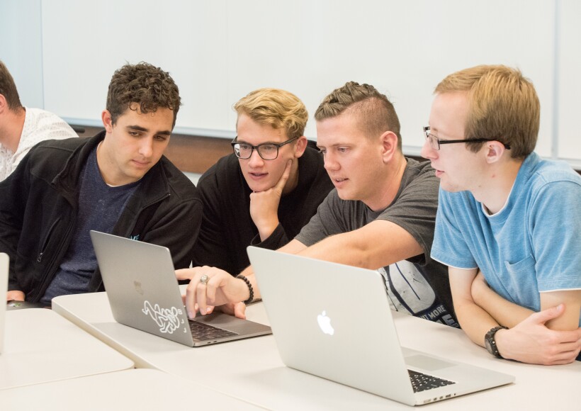 group of students looking at a laptop