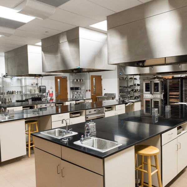 Three 18' work benches, portable induction burners (12), residential convection ovens (6), commercial double-stack convection oven (gas), dough proofer. Benchtop Product Development Space