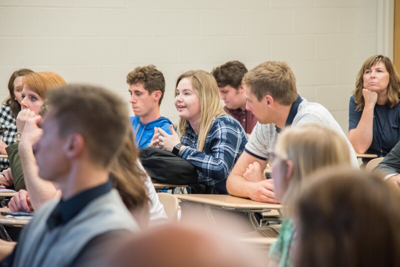 Students sitting at desks, in a discussion 