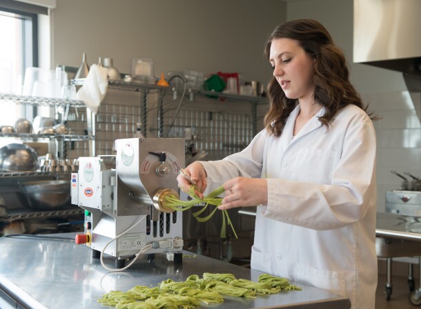 Student makes noodles with the noodle press.