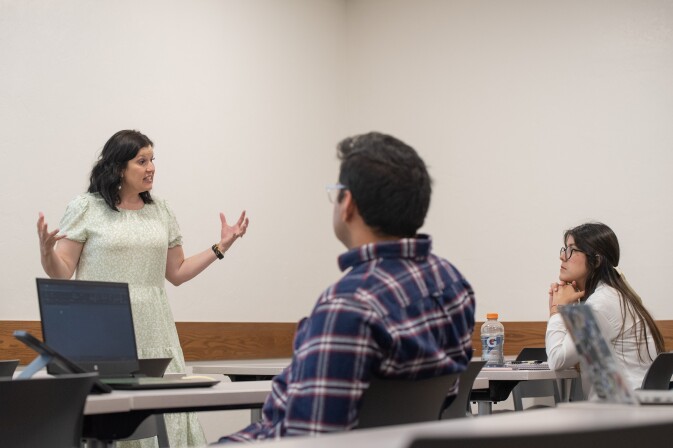 A female faculty members teaches a class of students about puclic health education and promotion.