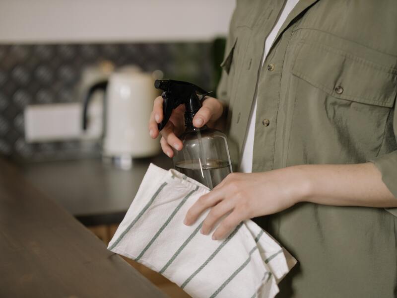 Person in Green Button Up Shirt Holding Clear spray bottle.