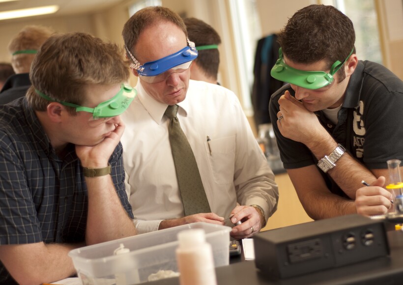 Two BYU-Idaho students listen to a faculty member discuss a research project in a classroom.