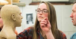 Art students sculpting a bust with clay.