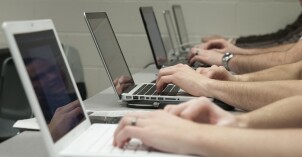 A group of students type on their laptops