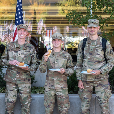 Four ROTC cadets smile while eating hotdogs on the BYU-Idaho campus.