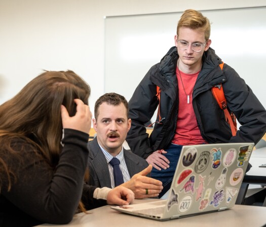 Sociology students talk with a professor.