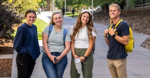 A group of 4 students on campus at BYU-Idaho smiling at the camera