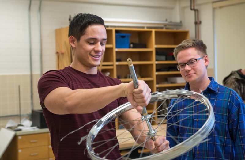 Physics students learn about rotational forces in a lab. Gordon Evans (maroon shirt)