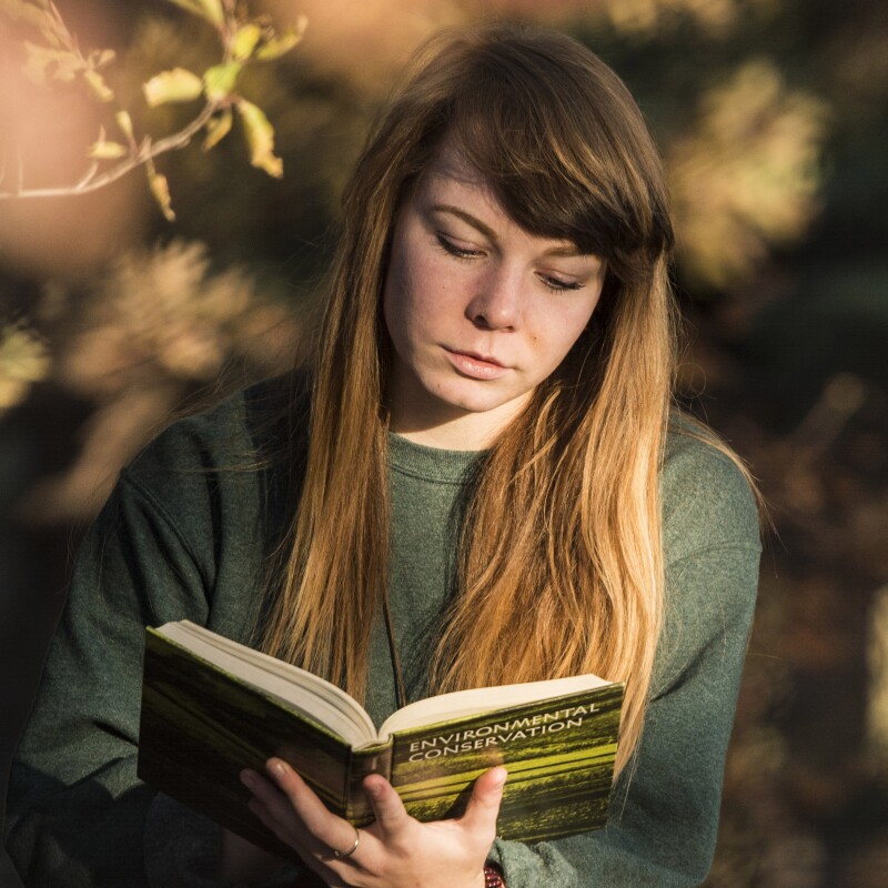 A student reads a book in the gardens