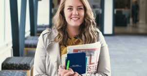 A News and Journalism student holds her notes as she smiles.