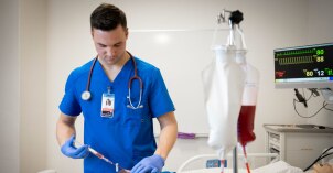 A nursing student practicing inserting an IV on a dummy arm
