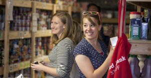 Two BYU-Idaho students smile while serving in a food bank at a Family Crisis Center service project.