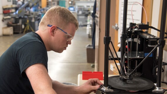 A Mechanical Engineering student views the 3D Printing machine