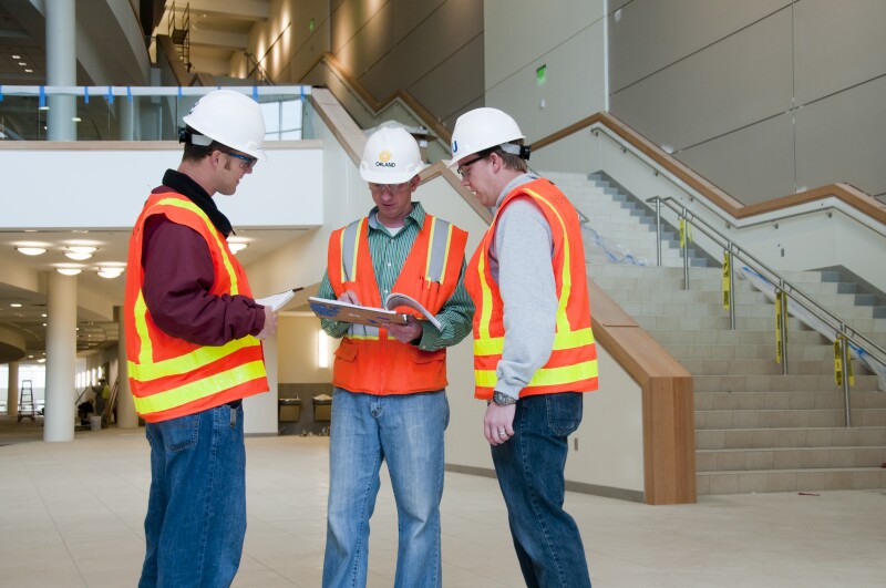 Construction Interns Aaron Howard (red jacket) and Ben Millet (right) talk with Doug Allen, one of Oakland contractors employees on the Auditorium.  