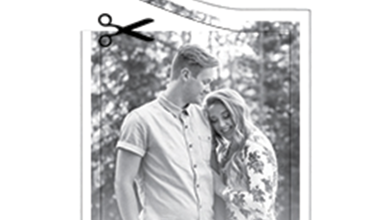 A black and white photograph of a young man and a young woman snuggling. The top border is being cut off by a pair of scissors.