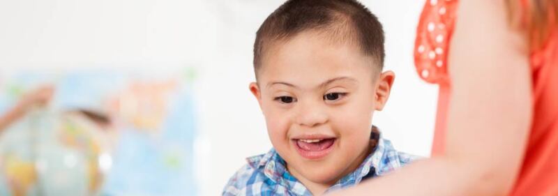 Teacher helps teach a student with down syndrome.